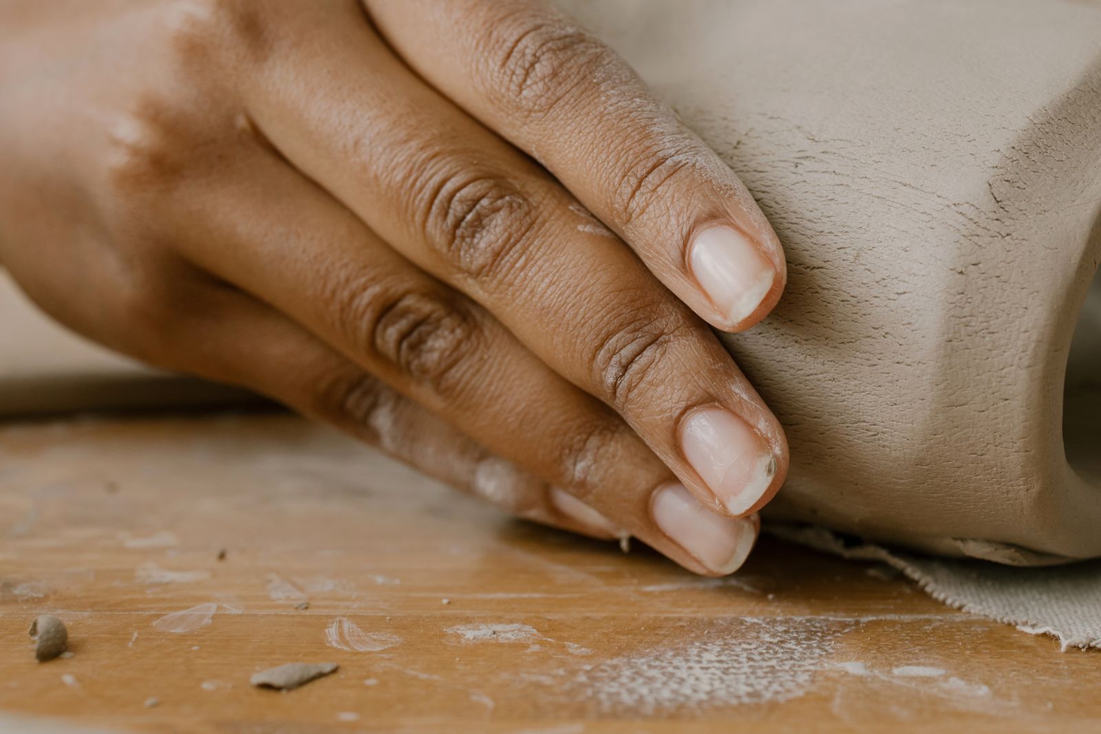 Mano moldeando una pieza de arcilla sobre una mesa