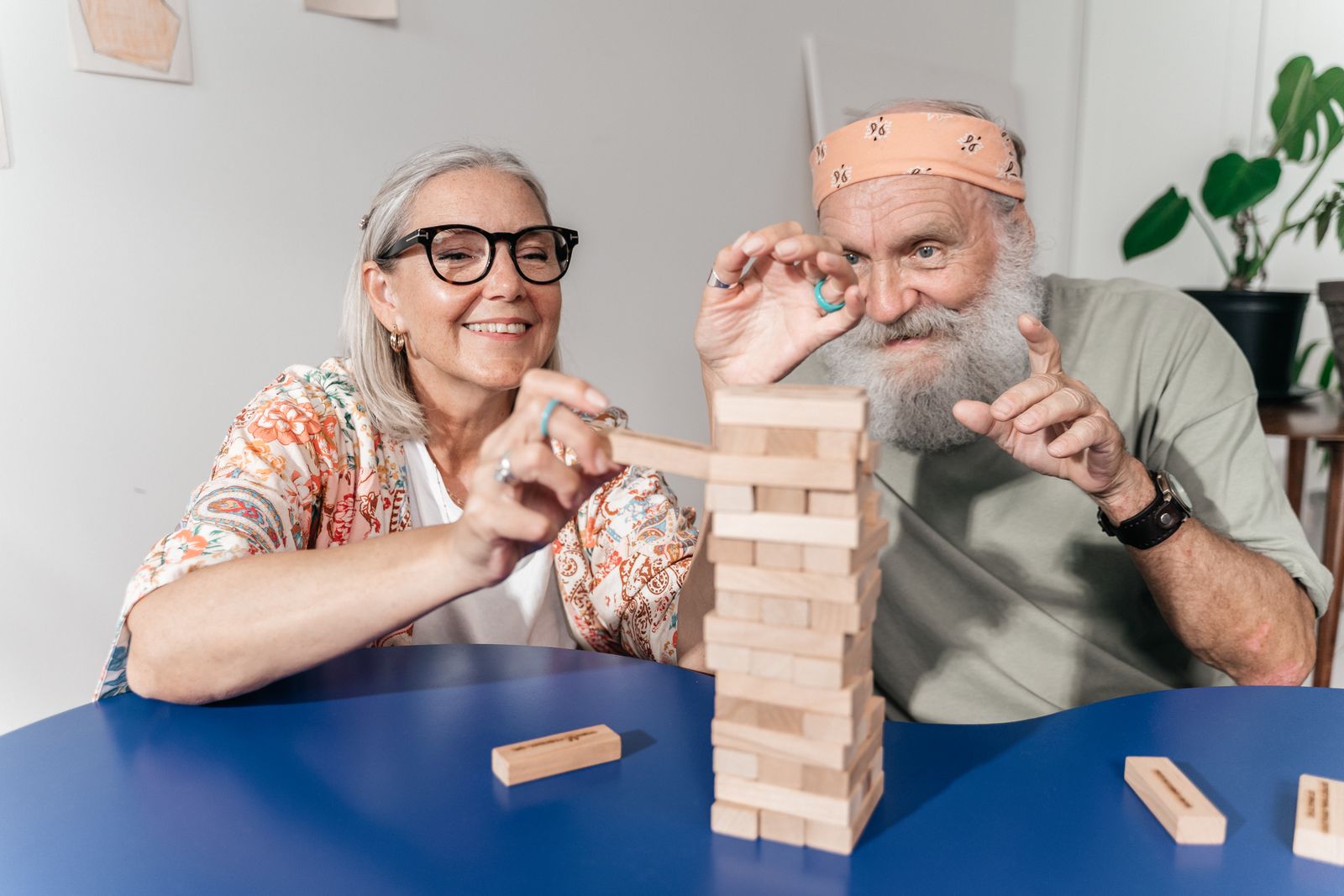 Pareja mayor jugando con una torre de bloques de madera en casa