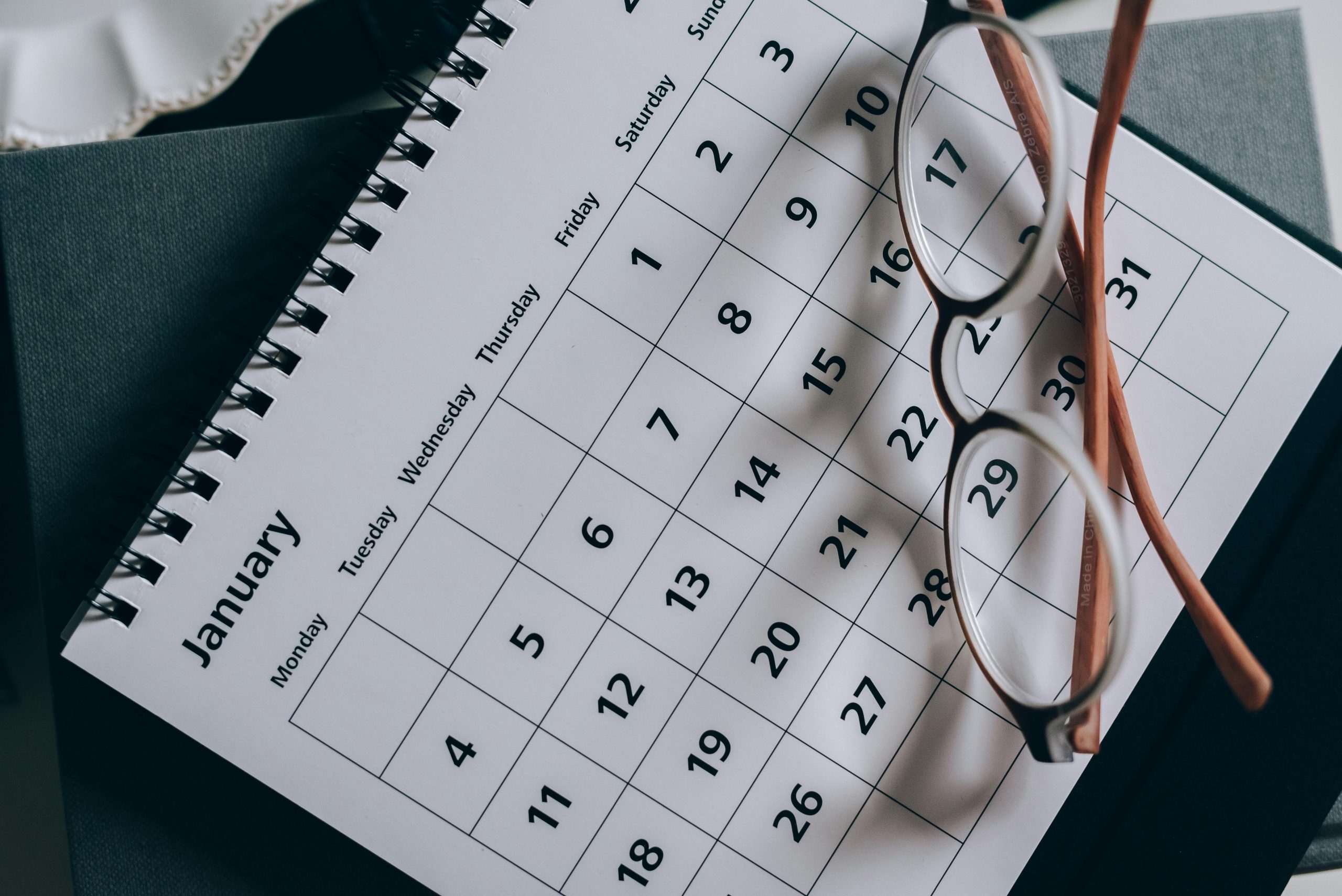 Calendario mensual con unas gafas apoyadas sobre la página